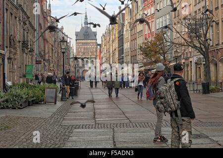 Gdansk, Pologne 31er octobre 2015, les gens regardent les pigeons à la rue Dluga à Gdansk. Peu de touristes a décidé de visiter le centre-ville historique de Gdansk. Le samedi 31 mai. Le temps est ensoleillé mais très froid, la température ne dépasse pas 5 degrés Celsius. Credit : Michal Fludra/Alamy Live News Banque D'Images