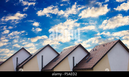 Des maisons résidentielles en ligne droite avec un ciel nuageux. Banque D'Images