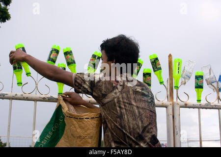 Un homme met les bouteilles en plastique sur une clôture pour recyclage mis à Skun, au Cambodge. Banque D'Images