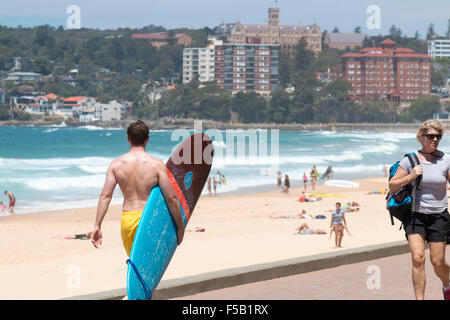 Mâle adulte surfer avec une planche de surf sur la promenade, Manly Beach Sydney, Australie Banque D'Images