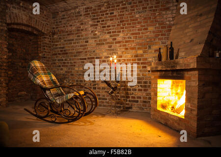 Rocking chair près de la cheminée en brique prix et des bougies Banque D'Images