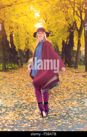 Femme blonde marcher sous des arbres en automne Banque D'Images