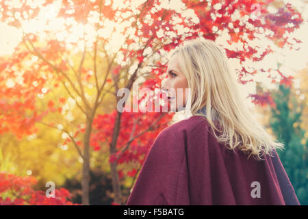 Femme blonde marcher sous des arbres en automne Banque D'Images