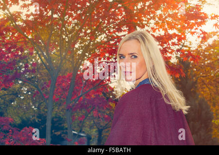 Femme blonde marcher sous des arbres en automne Banque D'Images