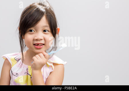 Cute Asian girl se brosser les dents, studio fond blanc isolé. Banque D'Images