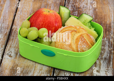 Déjeuner à l'école fort contenant du fromage roll, pomme rouge, les raisins et les bâtonnets de concombre Banque D'Images