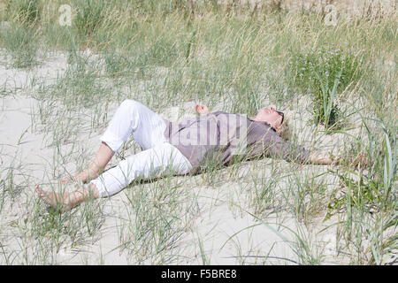 L'un des hauts couché dans les dunes sur la plage et regarde dans la distance Banque D'Images