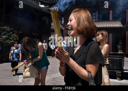 Dieu temple et pagode, temple bouddhiste à Shanghai, burning joss sticks, de l'encens. Une femme prie et rit de Chenghuang Miao ou Banque D'Images