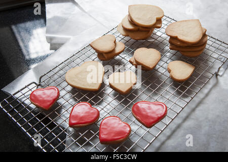 Petits et grands Sablés Heart-Shaped sur grille de refroidissement, certaines avec glaçure rouge Banque D'Images