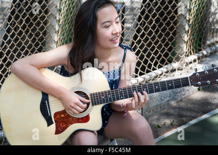 Teenage Girl Playing Guitar in Park Banque D'Images