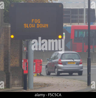 Une matrice d'autoroute illuminée signe qui indique 'RALENTISSEMENT' BROUILLARD sur l'A12, l'Est de Londres. Banque D'Images