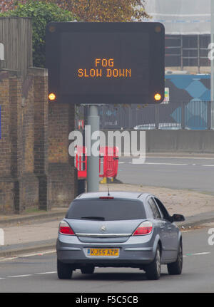 Une matrice d'autoroute illuminée signe qui indique 'RALENTISSEMENT' BROUILLARD sur l'A12, l'Est de Londres. Banque D'Images