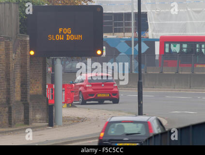 Une matrice d'autoroute illuminée signe qui indique 'RALENTISSEMENT' BROUILLARD sur l'A12, l'Est de Londres. Banque D'Images