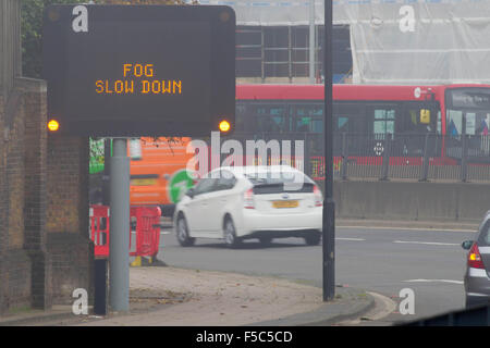 Une matrice d'autoroute illuminée signe qui indique 'RALENTISSEMENT' BROUILLARD sur l'A12, l'Est de Londres. Banque D'Images