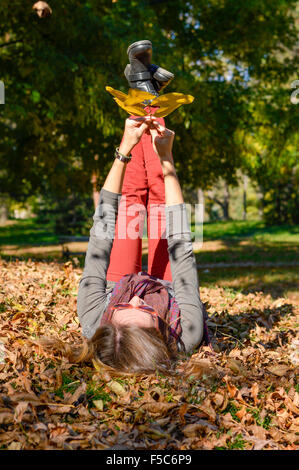 Happy girl lying sur jaune feuilles d'automne dans le parc Banque D'Images