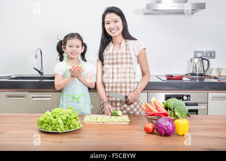 La famille, les enfants et les gens heureux concept - Mère et fille asiatique pour enfants dans la cuisine à la maison Banque D'Images