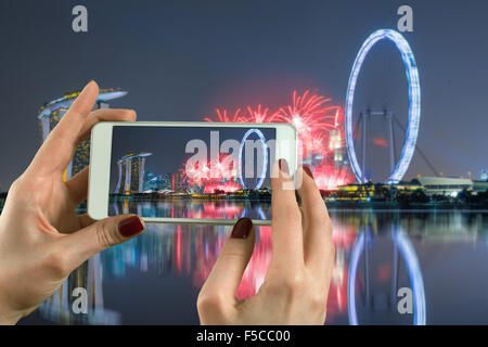 Vue arrière d'un couple avec un téléphone intelligent à l'appareil photo Marina Bay à Singapour Banque D'Images