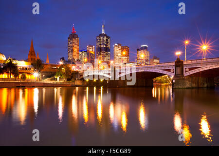 Les toits de Melbourne, en Australie avec la gare de Flinders Street et les Princes Bridge de l'autre côté de la rivière Yarra, dans la nuit. Banque D'Images