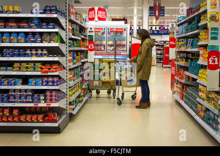 Woman shopping dans un supermarché Sainsbury's affichage des légumes en conserve Banque D'Images