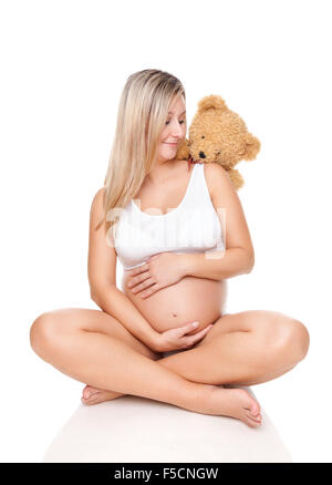 Portrait of a happy pregnant woman sitting on floor and holding belly Banque D'Images