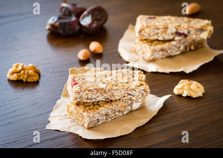 Barre granola ou barre d'énergie avec l'avoine, les dates et les écrous à l'arrière-plan en bois brun. Collation santé pour le yoga, le conditionnement physique ou haltérophiles pouvoir Banque D'Images