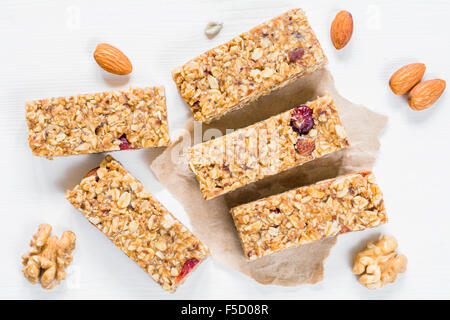 Barre granola ou barre d'énergie avec l'avoine, les dates et les écrous sur fond de bois blanc, vue du dessus Banque D'Images