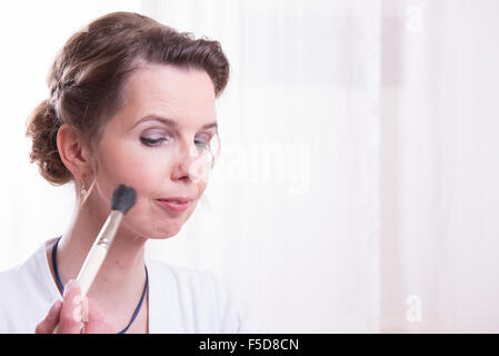 Jolie femme est de mettre son maquillage sur Banque D'Images