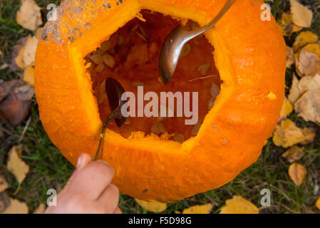 Les enfants de mêmes parents de garçons blonds hollowing out halloween citrouille à l'extérieur dans le jardin, assis sur la pelouse d'herbe d'automne, Banque D'Images