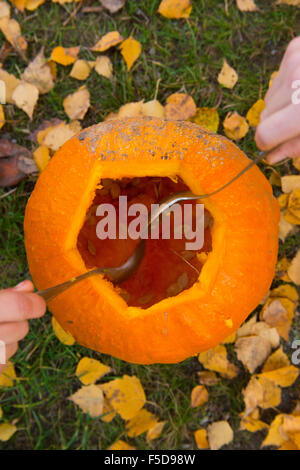 Les enfants de mêmes parents de garçons blonds hollowing out halloween citrouille à l'extérieur dans le jardin, assis sur la pelouse d'herbe d'automne, Banque D'Images