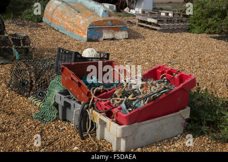 Conteneurs de matériel de pêche mixtes allongé sur un plage avec un bateau retourné en arrière-plan Banque D'Images