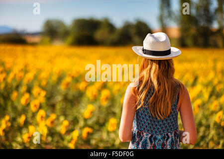 Une jeune femme dans un champ de tournesols près de Herrera de Pisuerga, Palencia, Castille Leon, Espagne. Banque D'Images