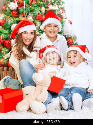 Portrait de la belle grande famille heureuse assis près de bel arbre de Noël décoré à la maison, porter du rouge Santa hats Banque D'Images