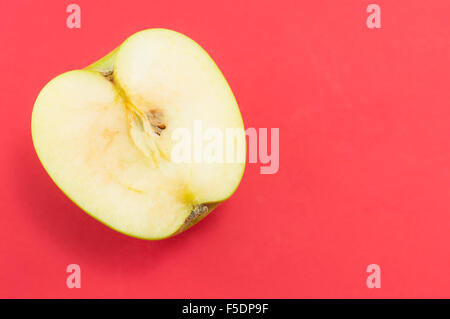 Moitié de pomme verte sur fond rouge. La saine alimentation Banque D'Images