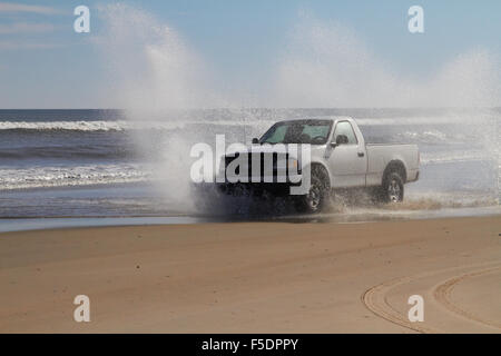 La conduite de camions à travers l'eau sur une plage Banque D'Images