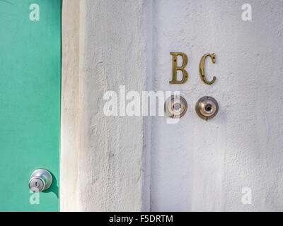 Close-up de deux cloches porte sur un mur en stuc blanc par un portail vert avec poignée, Santa Barbara, Californie, USA. Banque D'Images