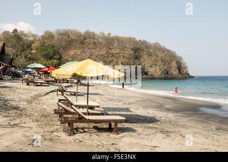 Parasols, chaises longues et à warungs, Pasir Putih ou plage de sable blanc, à Bali, Indonésie. Banque D'Images