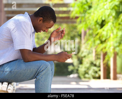 Portrait of a happy african american man laughing at mobile phone Banque D'Images