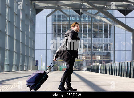 Portrait d'un jeune homme marchant avec valise à la station Banque D'Images