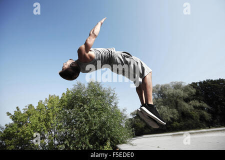 Jeune homme sportif sautant dans parc d'été Banque D'Images