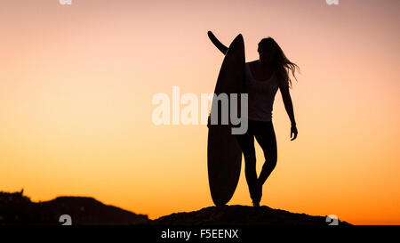 Silhouette d'une femme portant une planche de surf, Malibu, California, USA Banque D'Images