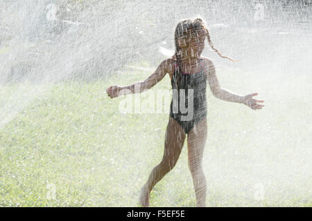 Fille jouant en aspersion d'eau Banque D'Images