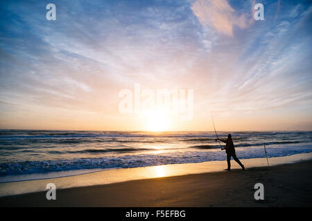 Silhouette d'un pêcheur sur la plage au coucher du soleil, Pescia Romana, lazio, Italie Banque D'Images