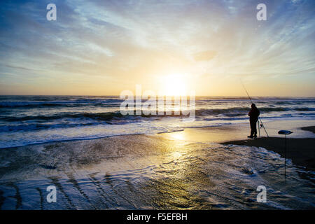 Silhouette d'un pêcheur sur la plage au coucher du soleil, Pescia Romana, lazio, Italie Banque D'Images