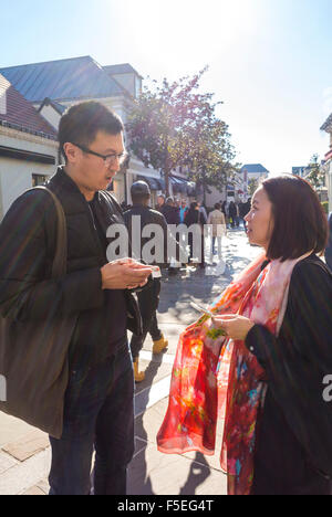 Paris, France, Couple chinois (M.R.) parler tout en Shopping Magasins de luxe dans la Vallée Village, magasins d'escompte, scène de rue, Iphone Banque D'Images