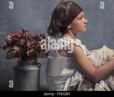 Vue latérale d'une fille assise avec son dos à un pot de fleurs Banque D'Images