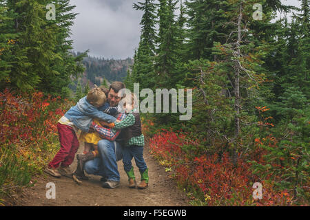 Trois enfants serrant leur père Banque D'Images