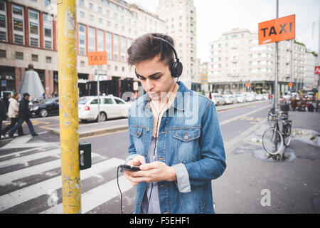 La moitié des jeunes longueur alternative beau modèle homme sombre en ville l'écoute de musique au casque et le smartphone, à la musique - à la baisse, de la technologie, concept relaxant Banque D'Images