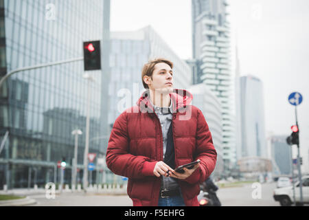 La moitié de la longueur d'un jeune beau caucasian businessman walking contemporain à travers la ville à l'aide d'une tablette donnant sur la gauche - la technologie, réseau, entreprise, finance concepts Banque D'Images