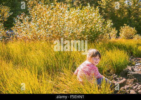 Girl sitting in tall grass Banque D'Images