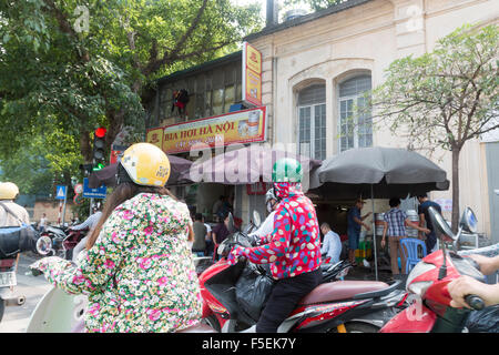 Cyclomoteurs scooter dans le centre-ville de Hanoi, capitale du Vietnam, coureurs portant des casques de vélo comme ils se lèvent Banque D'Images
